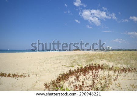 Large area of sand dunes with vegetation in foreground, ocean, Maroochy river mouth and Maroochydore high rise building in background. Pin cushion (rock island) by river mouth.