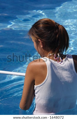 A young native girl cleaning the pool with a net.