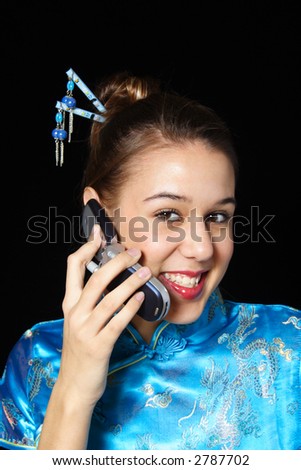A happy, cell phone user.  Mixed race girl in oriental dress.