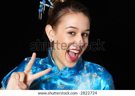 Mixed race girl in oriental dress flashes a big smile as she gives a peace sign.