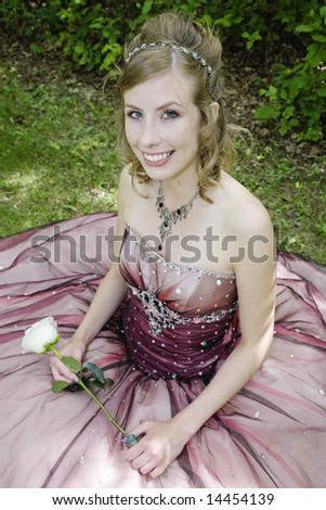Fair, freckled beauty in elegant formal prom dress, holding a single stem white rose.  Dappled light.