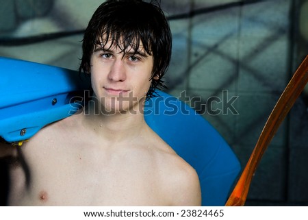 An up and coming young athlete with his trick kayak on his shoulder and paddle in his hand, still wet from his morning practice.