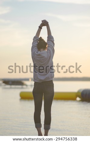 Leech Lake, Minnesota, United States - June 24, 2015: Young woman stretching her arms in the air while overlooking a lake landscape in Minnesota, United States