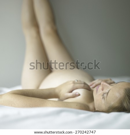 Naked pregnant woman lying on her back with legs up