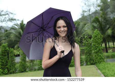Happy young woman walking in the rain with an umbrella.