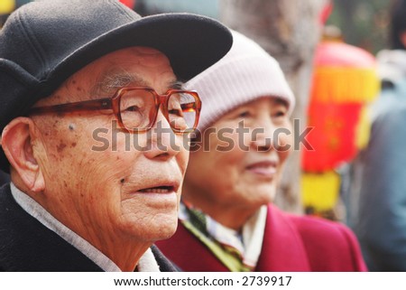 Chinese New Year celebrations in Qingdao, China - elderly Chinese couple watch a performance during a festival on the second day of the week-long vacation.