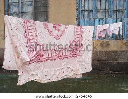 Patterned bed linen and children\'s clothing hanging on a clothes line