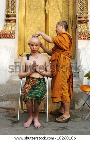 Thai man gets his head shaved by a monk during a Buddhist ordination ceremony.