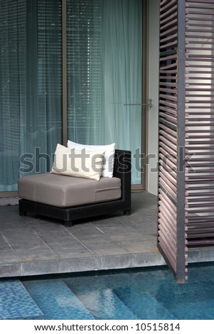 Peaceful place to relax: a chair on a balcony overlooking a private swimming pool.