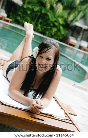 Woman in bikini relaxing on a deck chair.