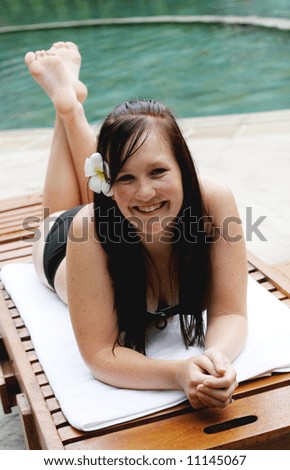 Woman in bikini relaxing on a deck chair.