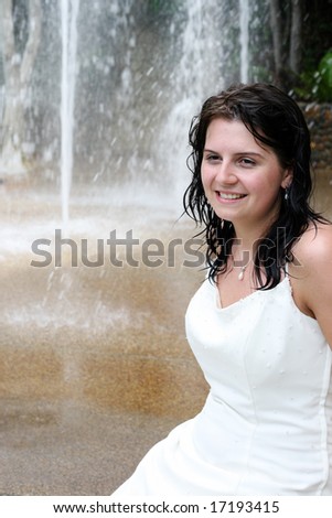Beautiful young bride next to a waterfall on her wedding day.