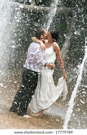Bride and groom dancing under a water fountain on their wedding day.
