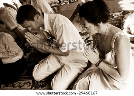 Western couple getting married during a traditional Buddhist wedding in Thailand.