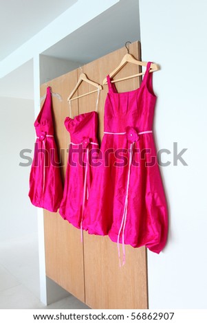 Bright pink bridesmaids dresses hanging up before a wedding.