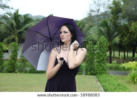 Gorgeous young woman walking in the rain with an umbrella.