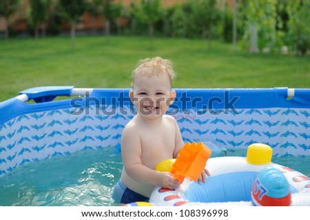 Curly haired blonde girl in swimming pool at the backyard