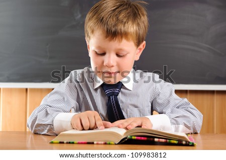 Cute elementary aged boy sitting at the desk with books