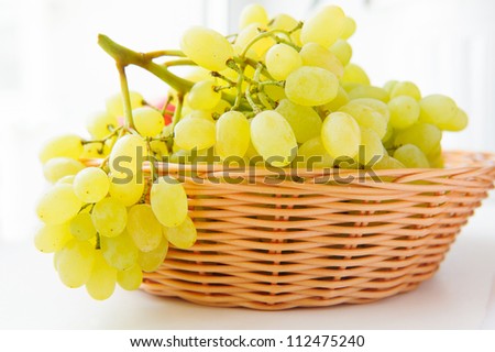 White grapes in basket over light background