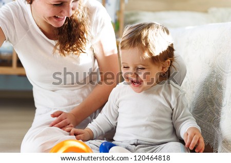 Young mother playing with her baby son at home