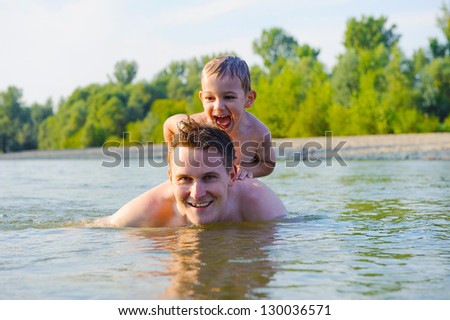 Young father and his little son swimming in river