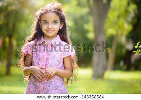 Portrait of hispanic girl with deep blue eyes in sunny park
