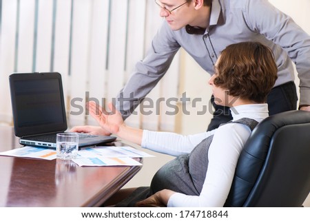 Young pregnant woman in dress working at office