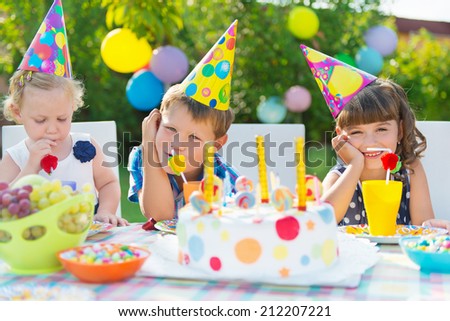 Three children celebrating birthday at outdoor party