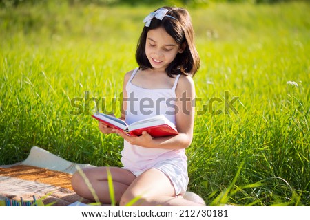 Happy child studying on nature with books