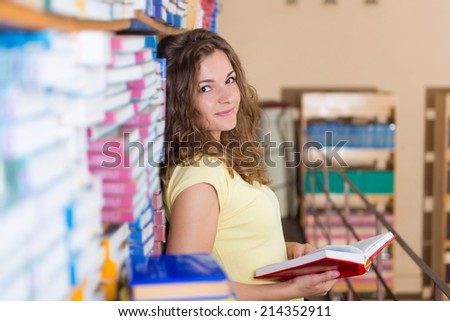 Portrait of clever student with books in college library