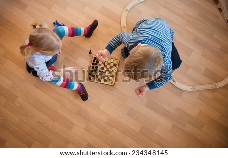 Brother and sister playing with chess. Photo from above