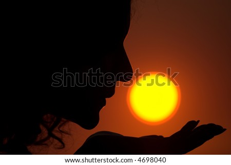 Young female is kissing the Sun during sunrise