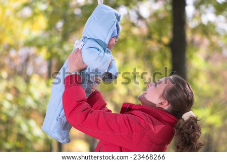 Young mother holds her baby in autumn forest