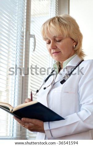 Senior doctor is makeng notes near hospital window