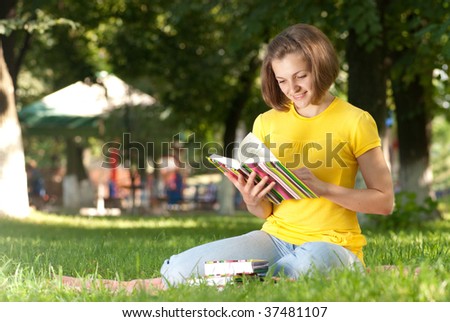 Young student is reading book in park