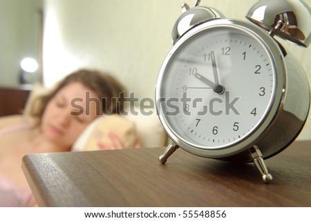 Young girl and alarm clock. Bedtime scene