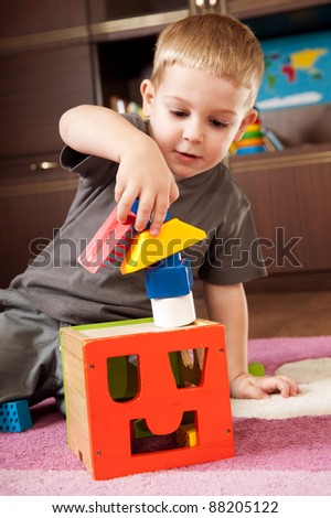 Little boy aged three is building a tower with toy blocks