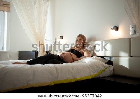 Young blonde pregnant woman relaxing in bedroom