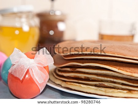 Easter eggs and stack of pancakes with tea and honey