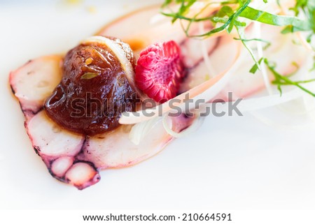 Cold appetizer of boiled octopus, cut into thin slices with a confit of cherry tomatoes, berries, grated cheese, julienne of fresh vegetables.