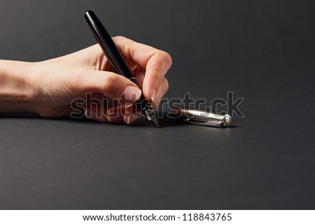 Hand with pen on black background