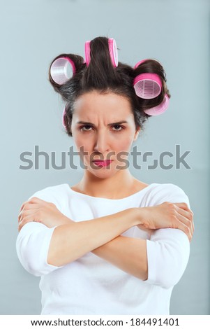 Portrait of housewife with hair curlers looking serious and angry.