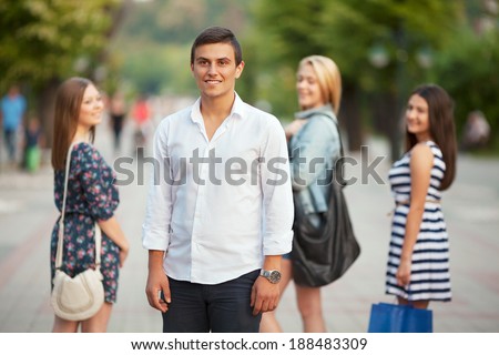 Group of young girls flirting with young man in the city.
