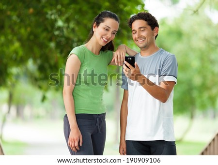 Checking smartphone while taking a break from exercising in the park