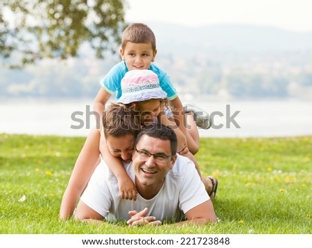 Portrait of happy family making a human pyramid in the meadow.