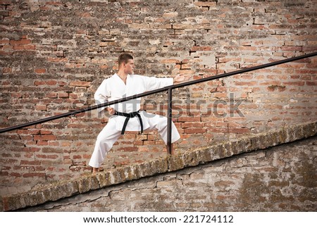 Young man in fighting stance in front of a brick wall
