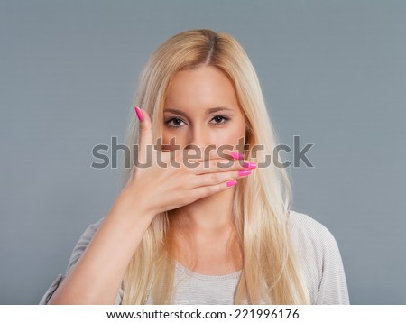 Studio shot of beautiful young woman with her hands covering mouth.