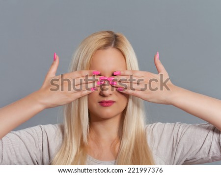 Studio shot of young woman with her hands covering eyes.