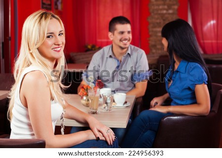 Beautiful young woman sitting with her friends in a cafe
