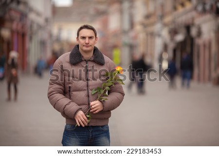 Handsome young man holding a single rose